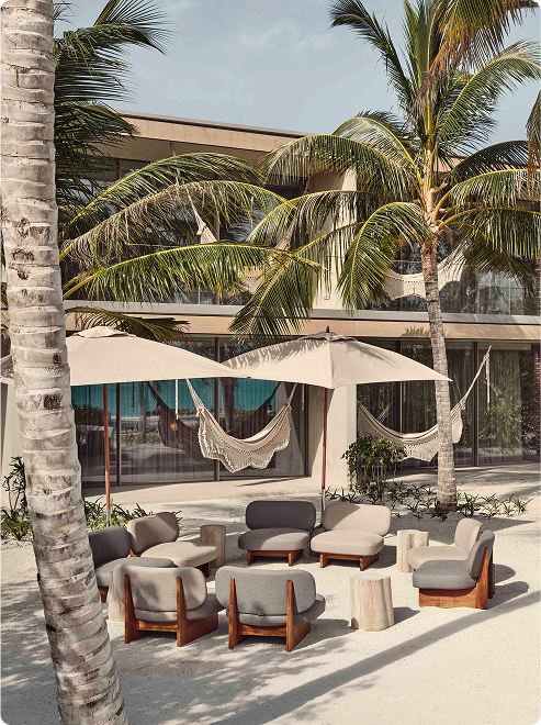 Circular seating under umbrellas on sand.