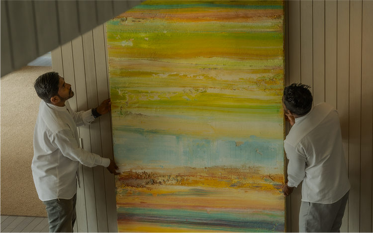 Two handlers position vibrant abstract painting.