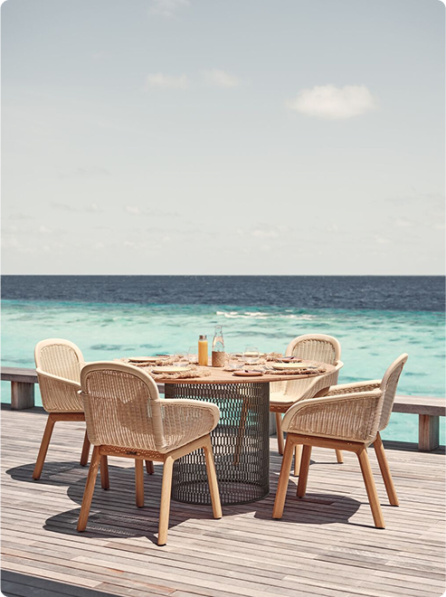 Oceanfront deck with wicker dining table.