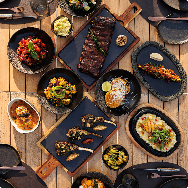 Grilled meats and sides on wooden table.