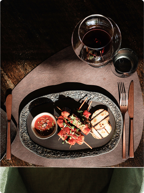 Skewered meat with grilled vegetables and sauce.