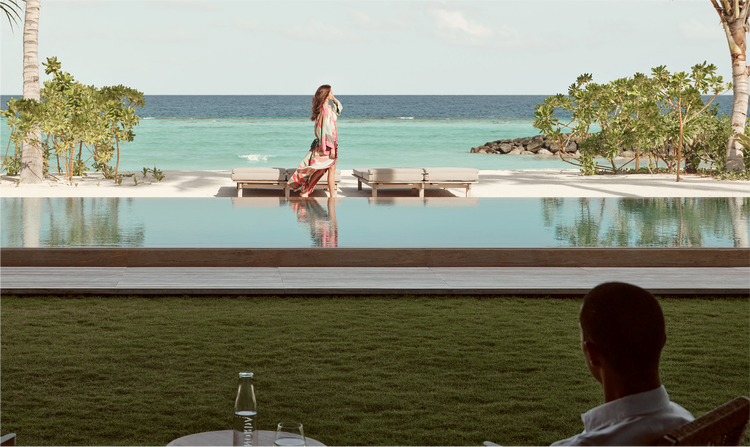 Woman walks past lounge chairs by ocean.