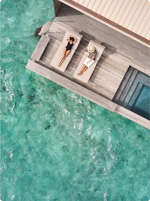 Two people lounge above turquoise water