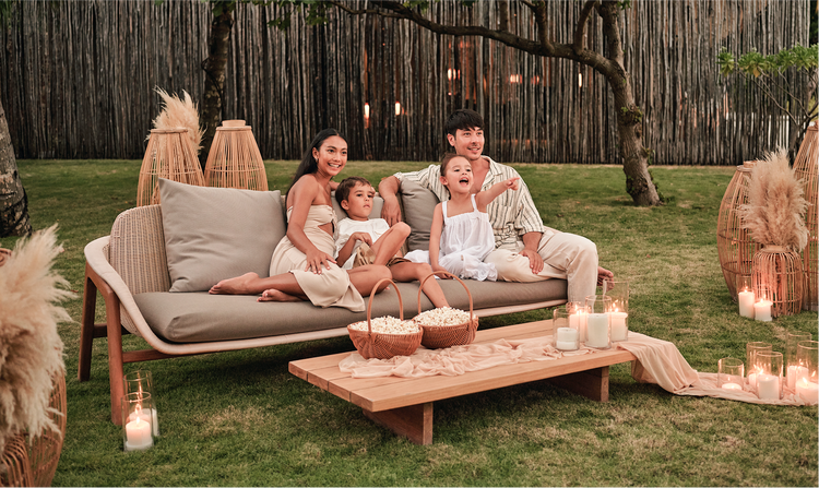 Family relaxes on outdoor garden couch.