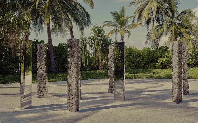 Reflective sculptures on sandy tropical path.