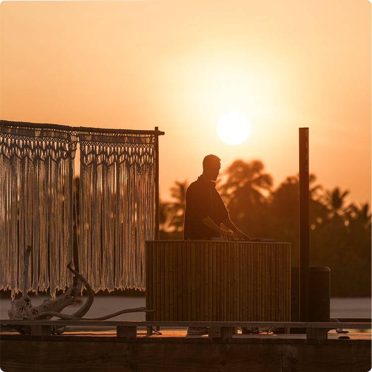 DJ-Performance vor einem Sonnenuntergang.