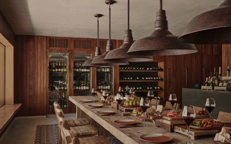 Communal table with wine and pendant lights.
