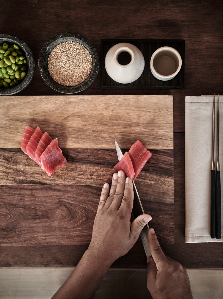 Tuna slicing beside soy and chopsticks.