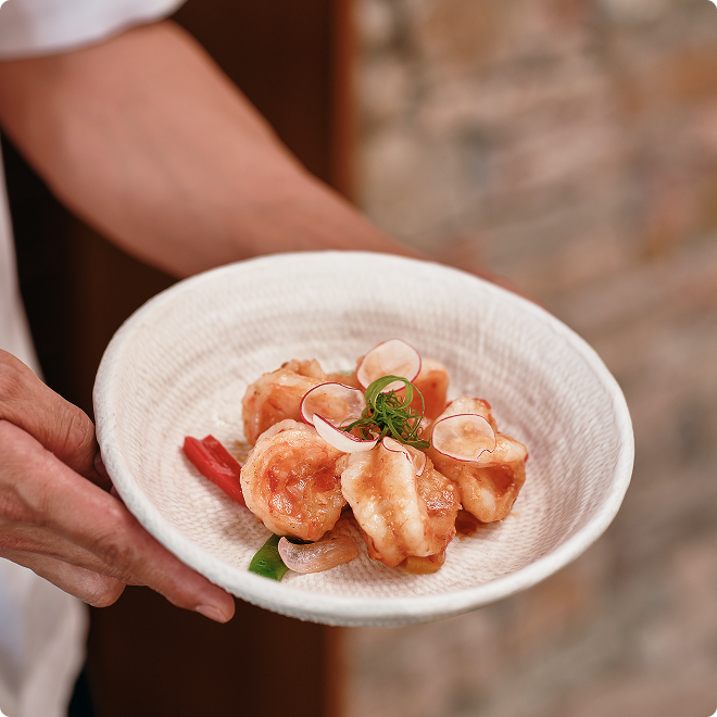 Garnished prawns in ceramic bowl setting.