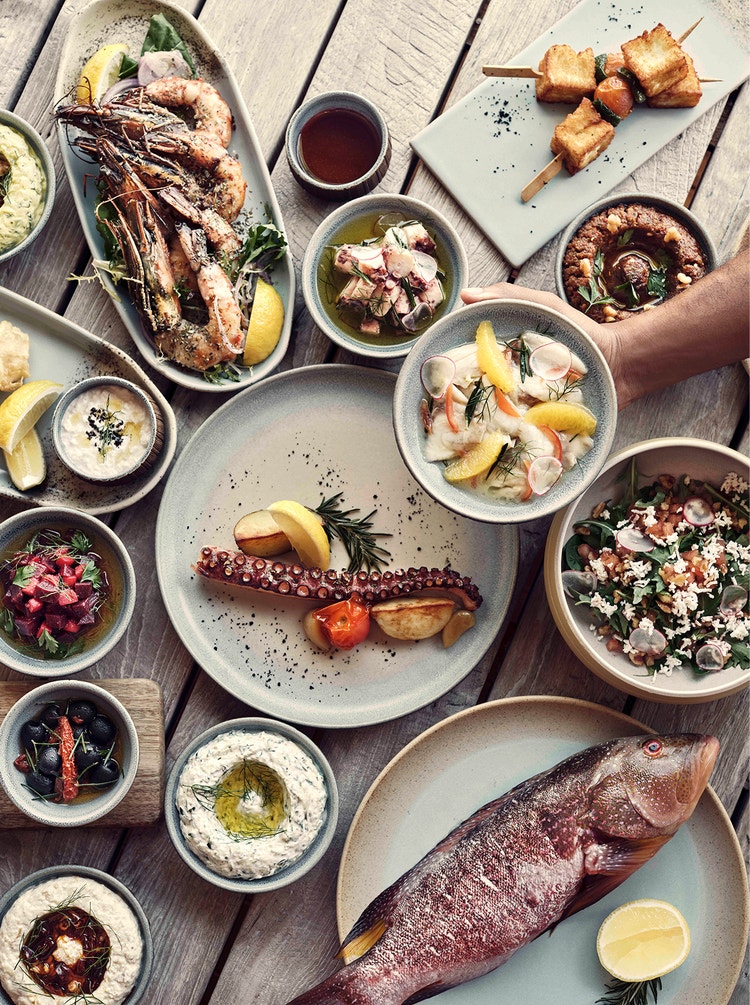 Grilled seafood and dips on rustic table.