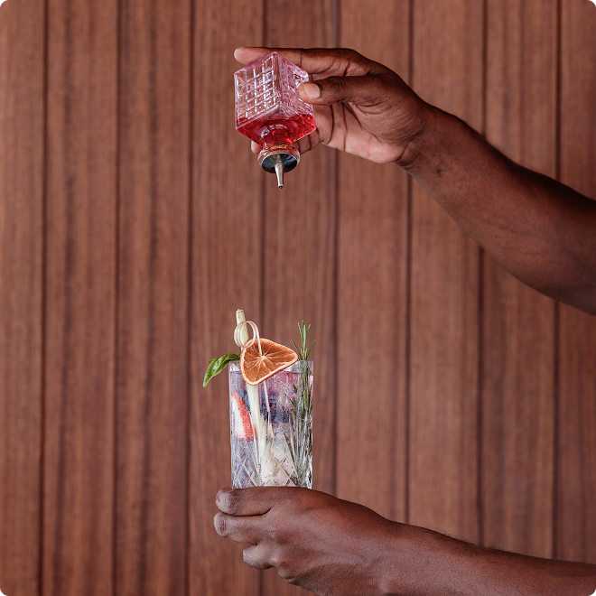 Pouring red infusion into herb cocktail.