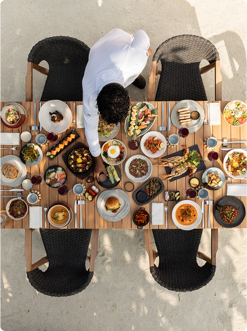 Chef arranges feast on outdoor table.