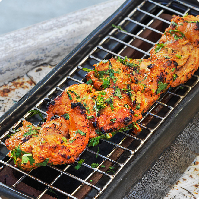 Spiced chicken grilling with fresh herbs.