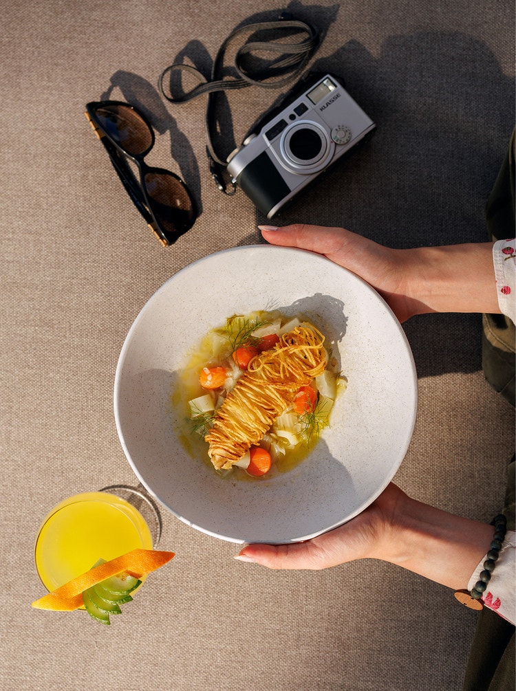 Person holds plated dish beside camera.