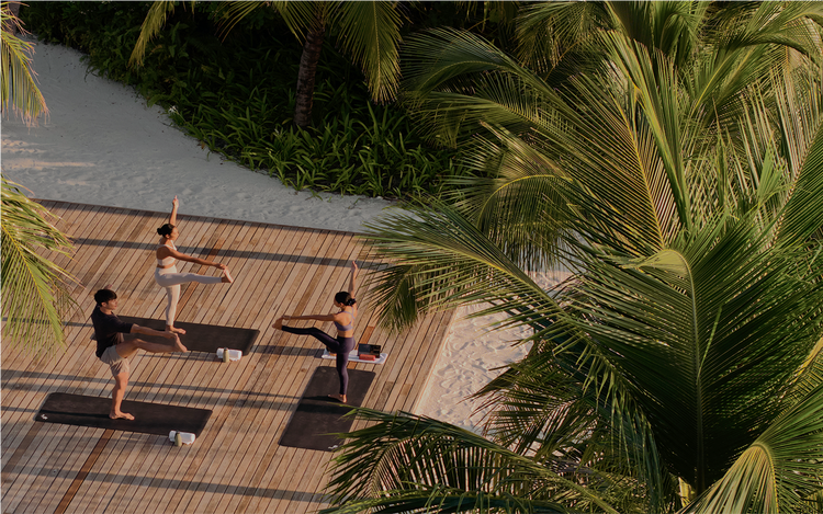 Group yoga on tropical wooden deck.
