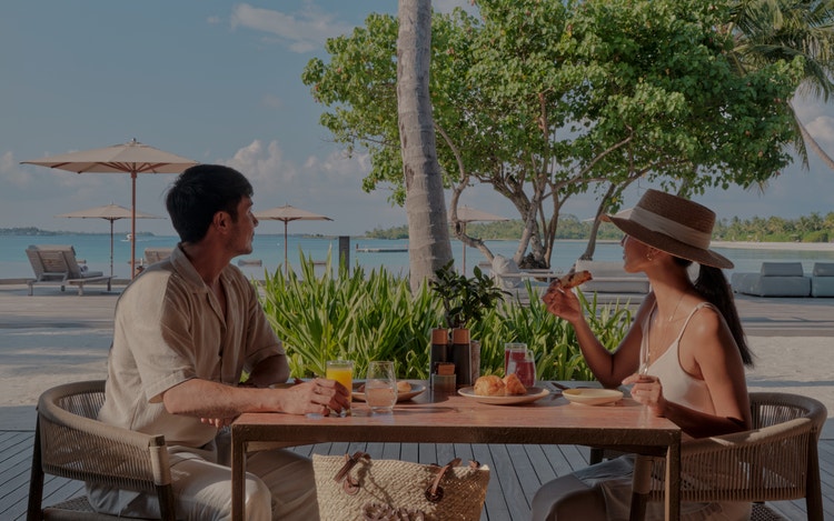 Couple enjoys breakfast by turquoise sea.