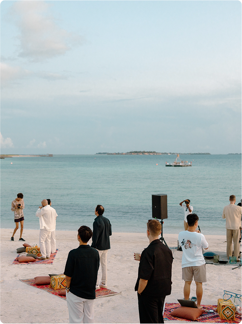 Group gathers on beach at sunset.