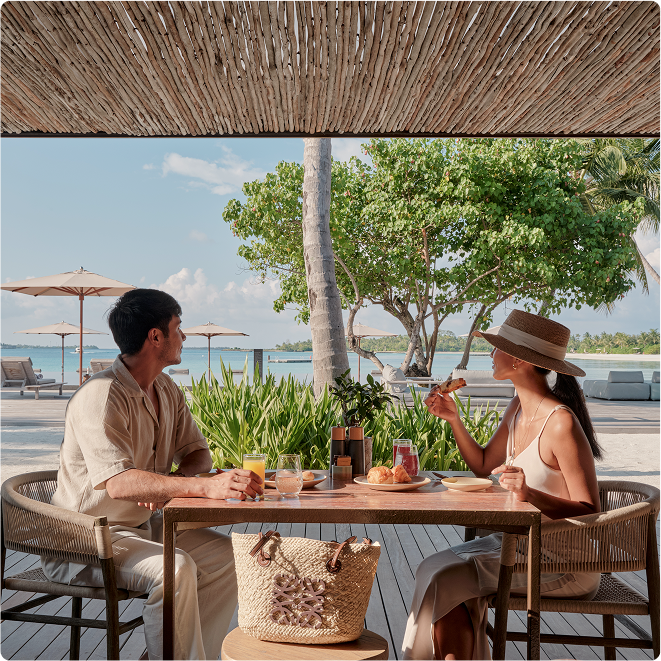 Two people enjoy breakfast by ocean