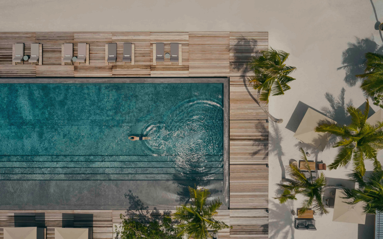 Swimmer glides through serene resort pool.
