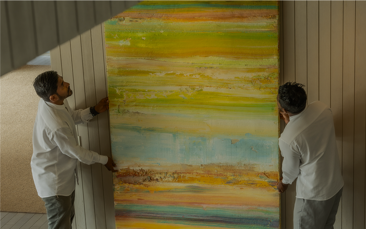 Two handlers position vibrant abstract painting.