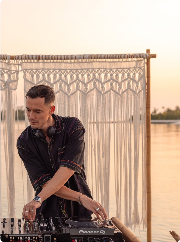 DJ performing outdoors at sunset