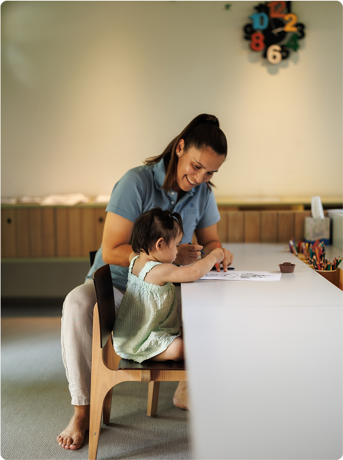 Smiling woman helps child color