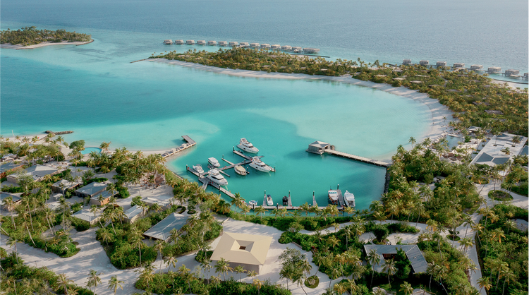 Aerial view of a tropical marina with turquoise waters, docked yachts, and lush resort villas.