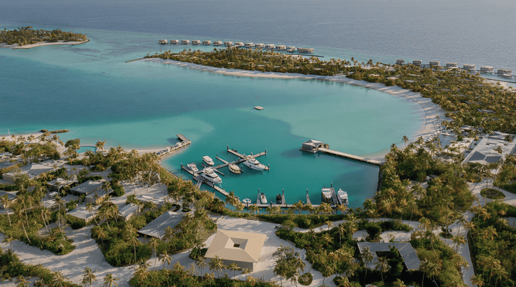Aerial view of a tropical marina with turquoise waters, docked yachts, and lush resort villas.