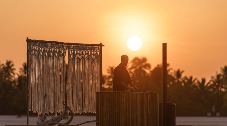 Resident DJ curates vinyl soundscape with a lake in the background.