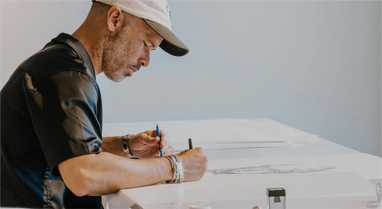 Artist sketches portrait with blue pencil.