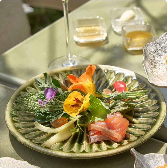 Salmon slices with edible floral garnish.