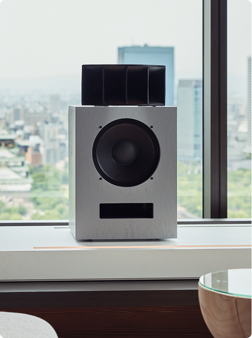 Metallic speaker on windowsill with skyline.