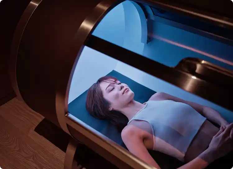 Guest reclines in illuminated therapy chamber.