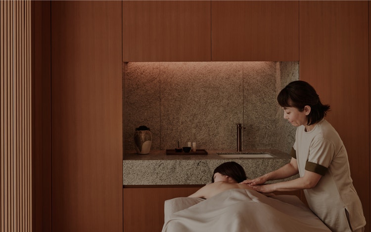 Spa therapist massages guest in tranquil room.